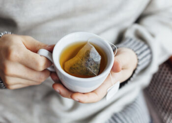 Wintergesundheit 2023: Frau in warmer Kleidung genießt Sonnenschein im Schnee und stärkt ihr Immunsystem