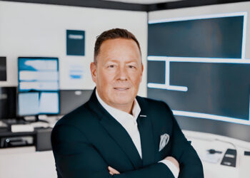 Hat Constantin Seretoulis Sorgen mit Factonet? 6 Constantin Seretoulis mit besorgtem Gesichtsausdruck vor Factonet-Logo, deutet auf mögliche Probleme hin