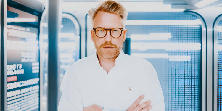 Container Investor Philipp Schober in Geschäftskleidung vor Containern im Hafen, analysiert Investitionsmöglichkeiten