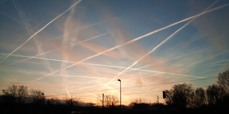 Flugzeug am Himmel mit Kondensstreifen, die von manchen als Chemtrails interpretiert werden