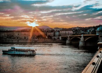 Firmengründung in Ungarn: Geschäftsmann mit Aktenkoffer vor ungarischer Flagge und Budapester Parlament