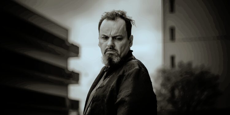 Rogo DeVille: Rockpoet & Mutmacher - Seine bewegte Story 1 Rogo DeVille, Rockpoet und Mutmacher, steht auf einer Bühne mit Gitarre und singt leidenschaftlich ins Mikrofon