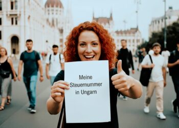 Frau zeigt Dokument mit deutschem Text 'Meine Steuernummer in Ungarn' vor Budapester Parlamentsgebäude
